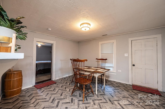 dining space featuring parquet flooring and a textured ceiling