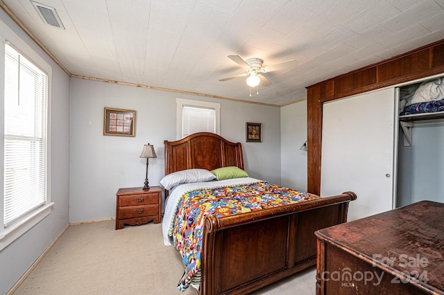 bedroom with a closet, light colored carpet, ceiling fan, and crown molding