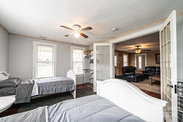 bedroom featuring ceiling fan, wood-type flooring, a textured ceiling, and french doors