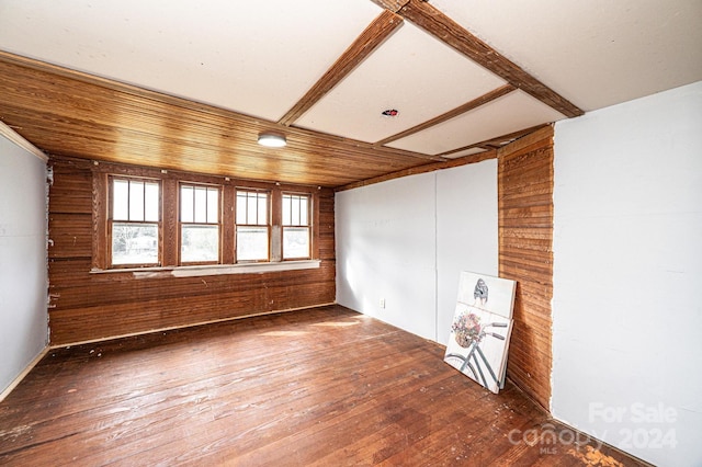 empty room with dark hardwood / wood-style flooring and wooden walls