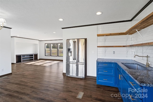 kitchen with dark stone counters, blue cabinets, sink, dark hardwood / wood-style flooring, and stainless steel fridge with ice dispenser