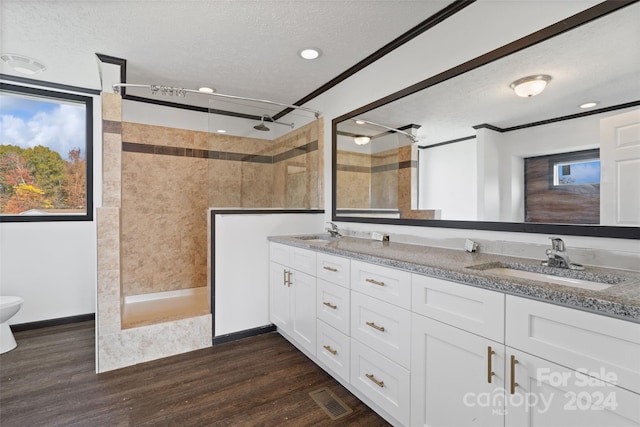 bathroom featuring a textured ceiling, vanity, wood-type flooring, and tiled shower