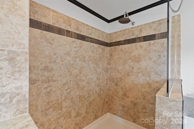 bathroom with crown molding, a textured ceiling, and a tile shower