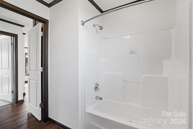 bathroom with washtub / shower combination, hardwood / wood-style floors, and crown molding