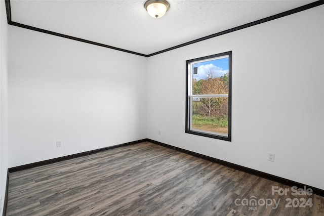 empty room with crown molding, dark wood-type flooring, and a textured ceiling