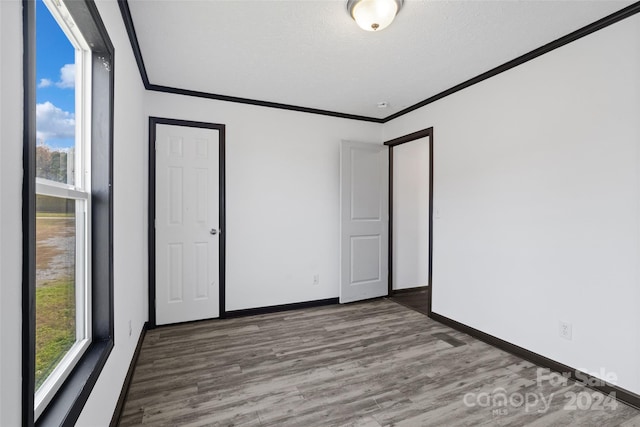 spare room with hardwood / wood-style floors, a textured ceiling, and ornamental molding