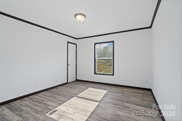 empty room with wood-type flooring and crown molding