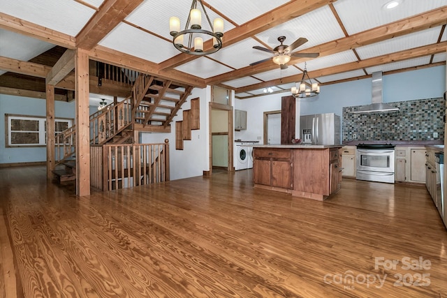 kitchen featuring decorative light fixtures, decorative backsplash, a center island, stainless steel appliances, and wall chimney exhaust hood