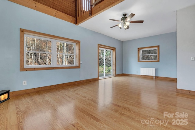 unfurnished living room featuring radiator heating unit, ceiling fan, and light hardwood / wood-style flooring