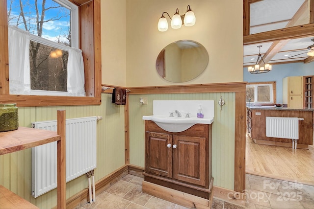 bathroom with beam ceiling, vanity, radiator, and an inviting chandelier