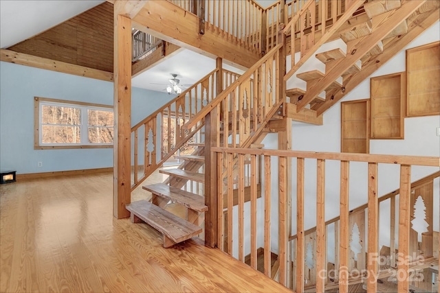 stairway with hardwood / wood-style flooring, a high ceiling, and ceiling fan