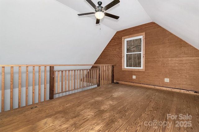 additional living space with lofted ceiling, wood-type flooring, ceiling fan, and wood walls