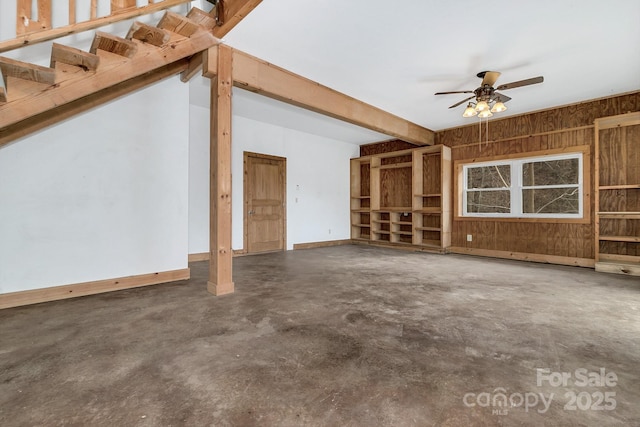 unfurnished living room with ceiling fan and wood walls