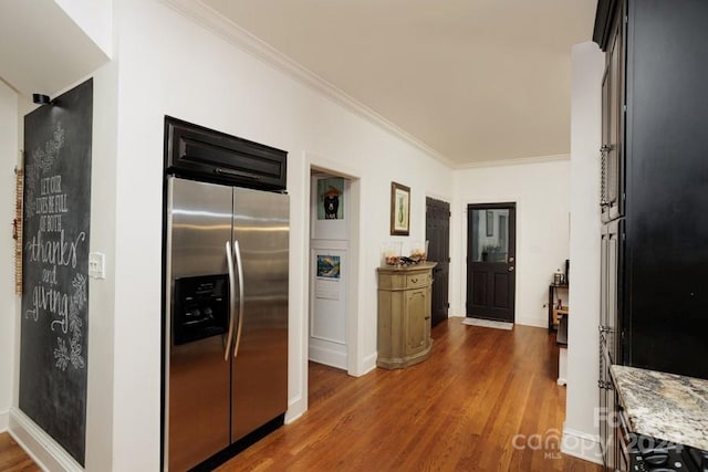 kitchen featuring dark hardwood / wood-style floors, crown molding, light stone countertops, and stainless steel refrigerator with ice dispenser