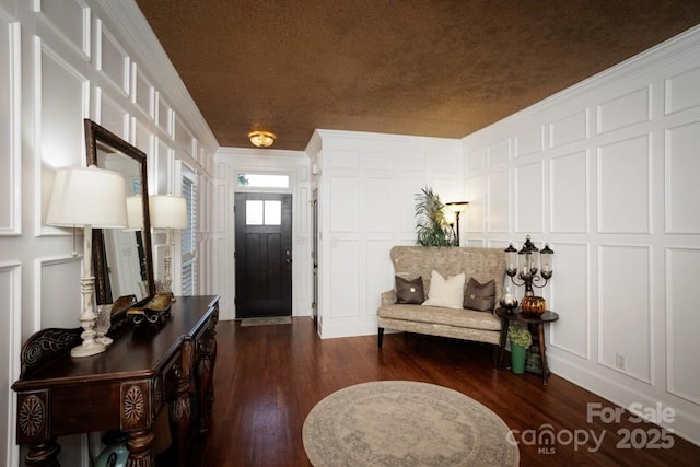 foyer entrance featuring crown molding, dark wood-style flooring, and a decorative wall