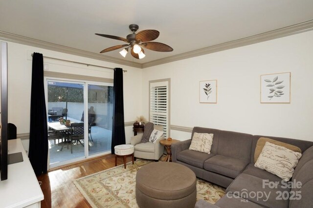 living area with a ceiling fan, ornamental molding, and wood finished floors