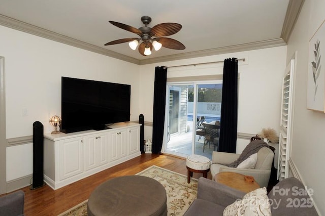 living area featuring baseboards, a ceiling fan, crown molding, and wood finished floors