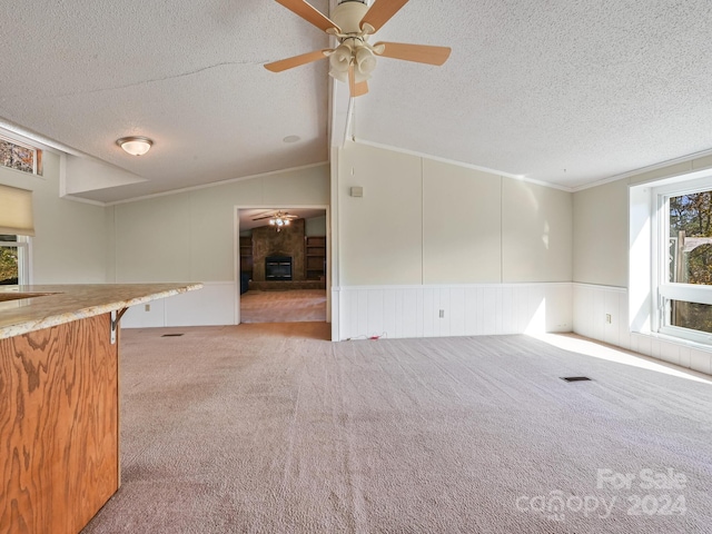 interior space featuring light carpet, a textured ceiling, vaulted ceiling, and ornamental molding