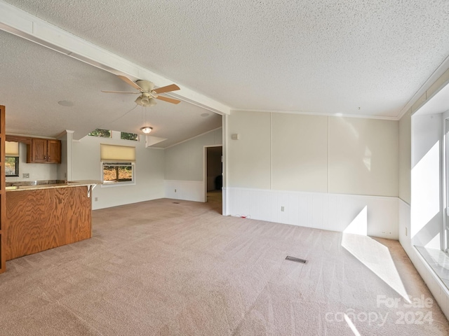 unfurnished living room with vaulted ceiling with beams, light carpet, ceiling fan, and a textured ceiling