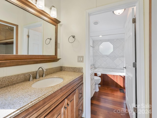 bathroom with toilet, vanity, a bath, and wood-type flooring