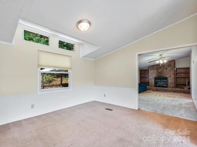 unfurnished living room with carpet, crown molding, vaulted ceiling, a textured ceiling, and a fireplace