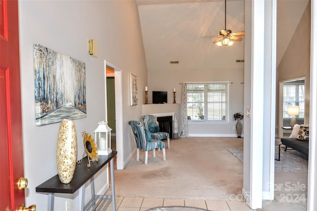 carpeted entryway with ceiling fan and high vaulted ceiling