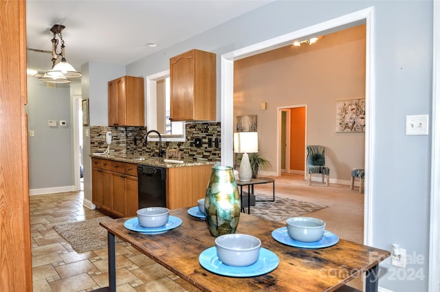 kitchen featuring sink, decorative backsplash, black dishwasher, decorative light fixtures, and light stone counters