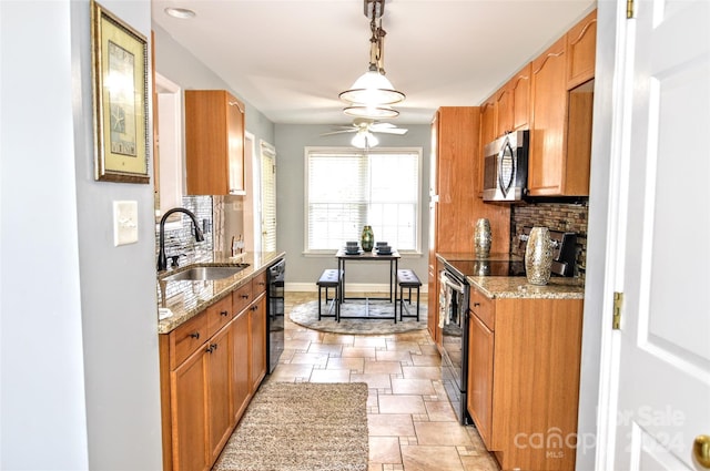 kitchen with light stone counters, sink, decorative light fixtures, and appliances with stainless steel finishes