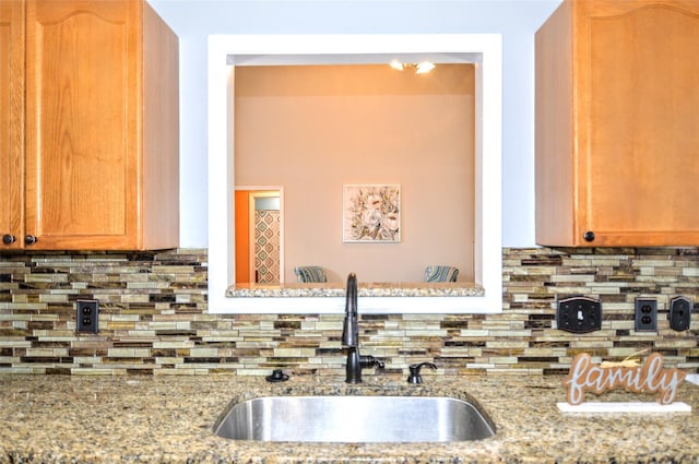 kitchen featuring decorative backsplash, light stone countertops, and sink