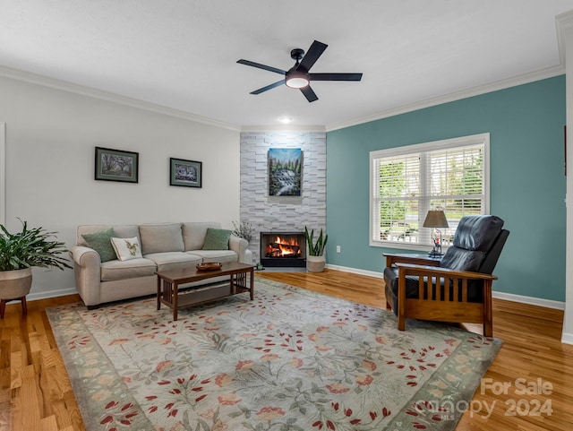 living room featuring ceiling fan, crown molding, wood-type flooring, and a fireplace