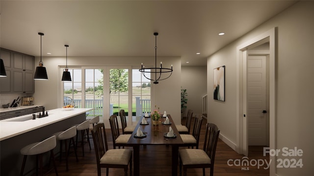 dining space with sink, dark hardwood / wood-style floors, and a notable chandelier