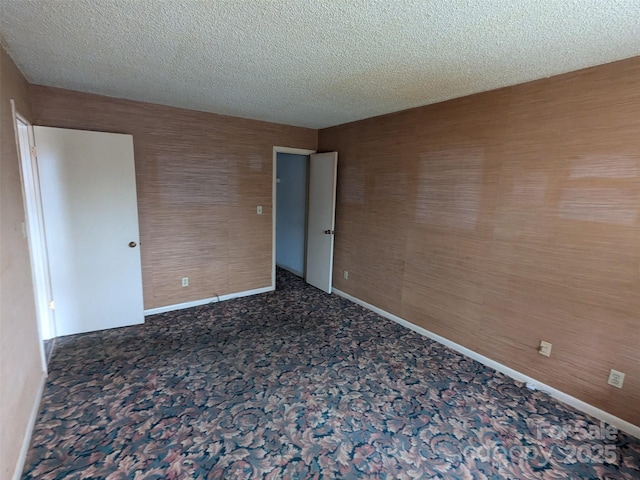 empty room featuring dark colored carpet and a textured ceiling