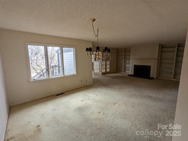 unfurnished living room featuring an inviting chandelier, carpet flooring, and a textured ceiling