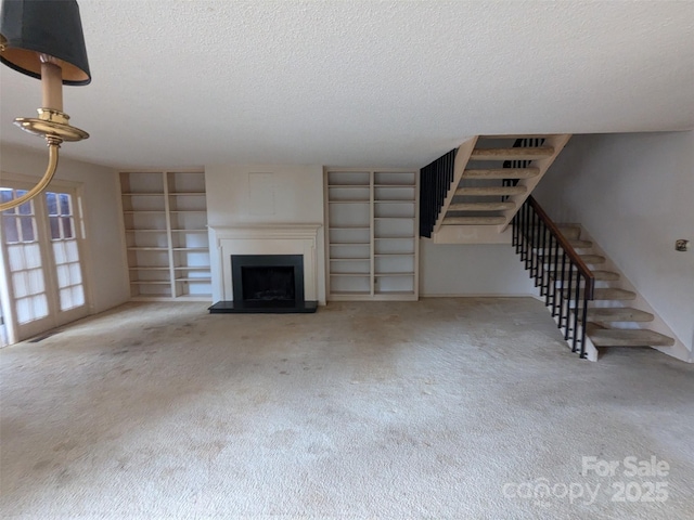 unfurnished living room with carpet floors, a textured ceiling, and built in shelves