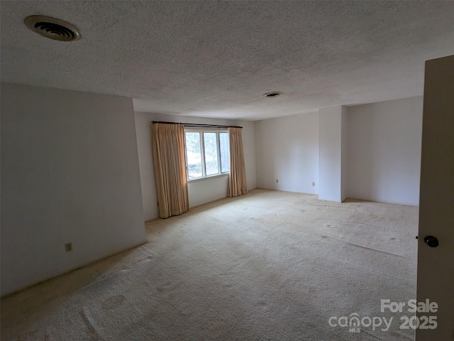 spare room with light colored carpet and a textured ceiling