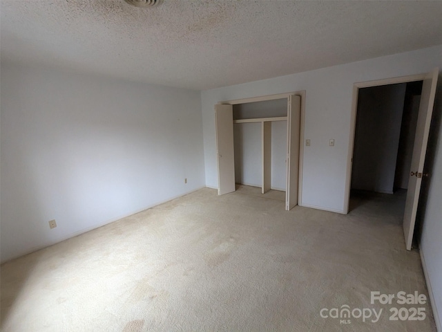 unfurnished bedroom featuring light colored carpet, a closet, and a textured ceiling