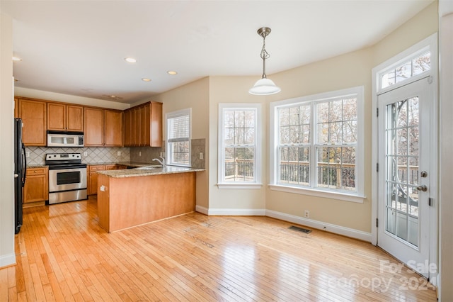 kitchen featuring kitchen peninsula, light stone countertops, stainless steel range with electric stovetop, pendant lighting, and light hardwood / wood-style flooring