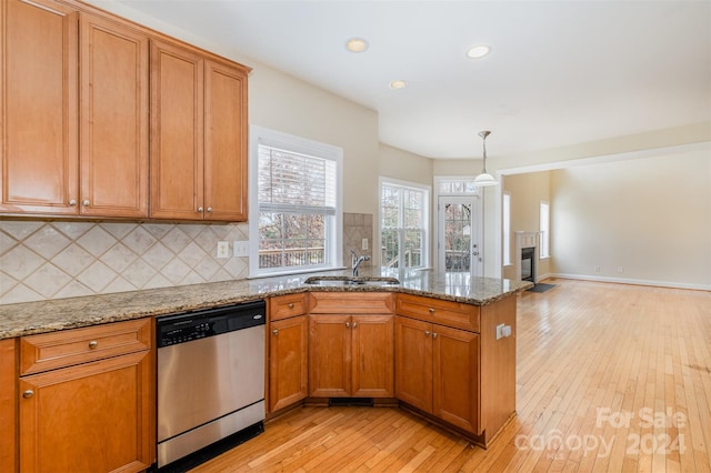 kitchen featuring dishwasher, light stone countertops, light wood-type flooring, and sink