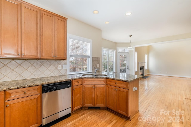 kitchen with dishwasher, light stone countertops, sink, and light hardwood / wood-style flooring