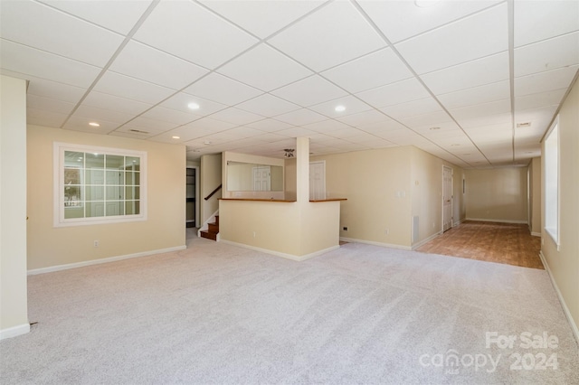 basement featuring a paneled ceiling and light colored carpet