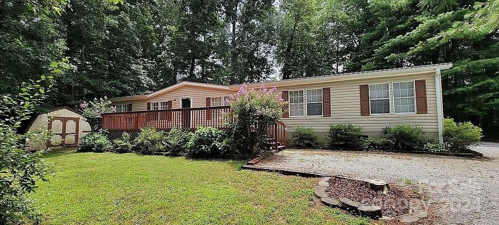 view of front facade featuring a front lawn, a deck, and a storage unit