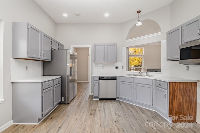 kitchen featuring gray cabinetry, sink, stainless steel appliances, and light wood-type flooring