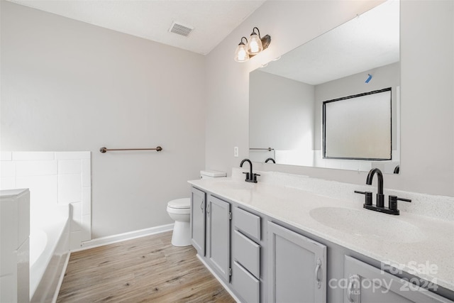 bathroom featuring a bath, vanity, wood-type flooring, and toilet