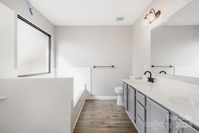 bathroom featuring hardwood / wood-style floors, a washtub, toilet, and vanity