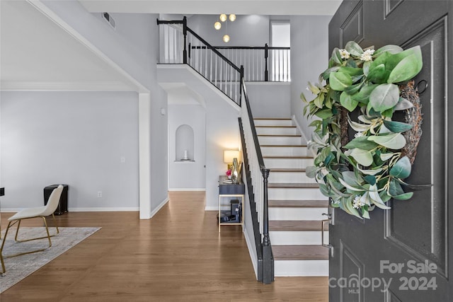 stairway with hardwood / wood-style floors and crown molding