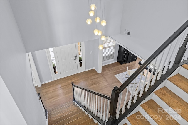 foyer with hardwood / wood-style floors, a notable chandelier, and a towering ceiling