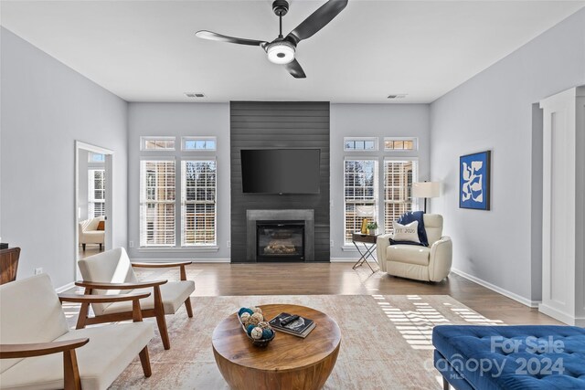 living room with ceiling fan, a fireplace, and hardwood / wood-style flooring