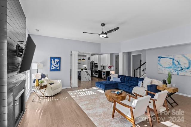 living room featuring ceiling fan, a fireplace, and light hardwood / wood-style flooring