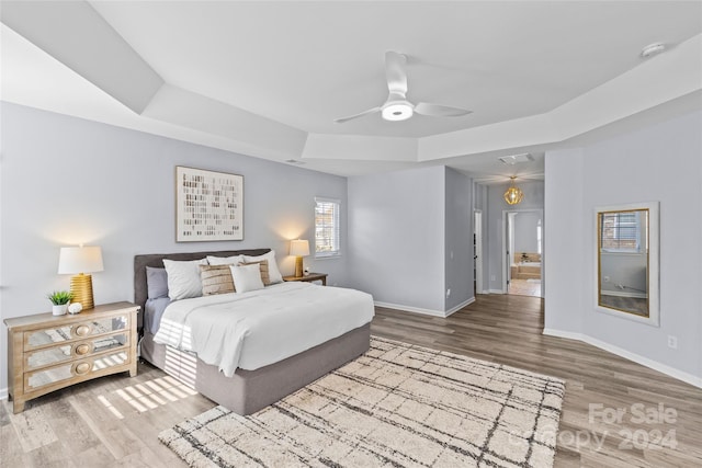 bedroom with a raised ceiling, ceiling fan, and hardwood / wood-style flooring