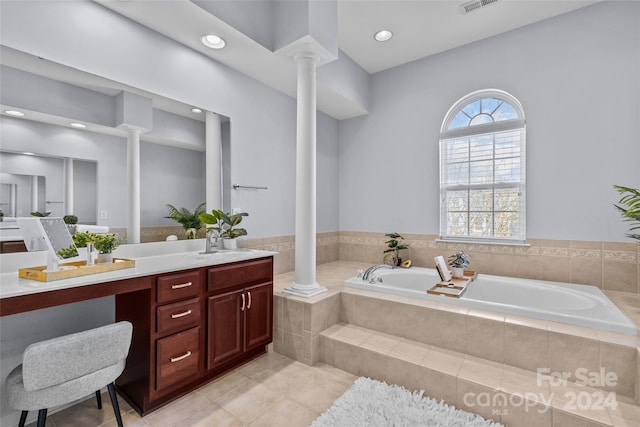 bathroom with tile patterned floors, ornate columns, vanity, and tiled tub